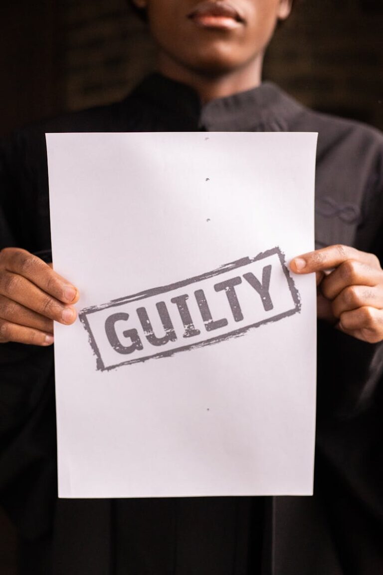 A close-up of a judge holding a document with a 'Guilty' verdict in a courtroom setting.